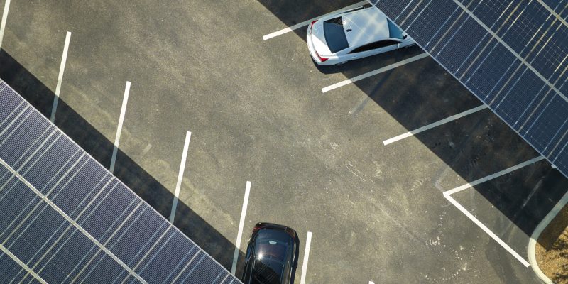 Solar carport canopy covering parked vehicles with integrated EV charging